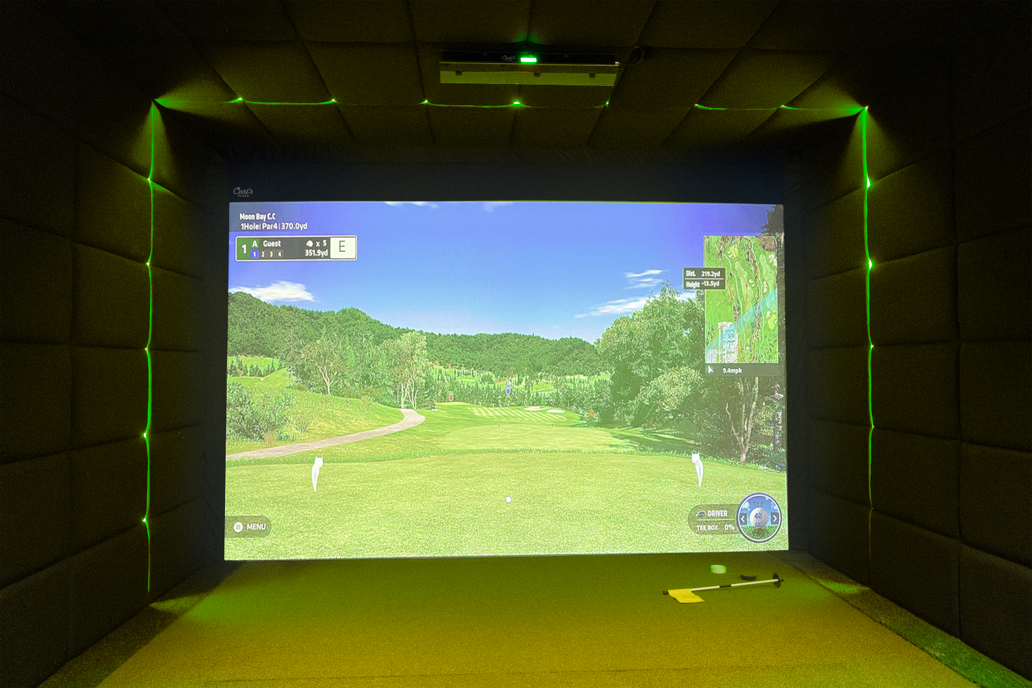 Golf simulator showing a tee shot with green strip lighting surrounding the screen