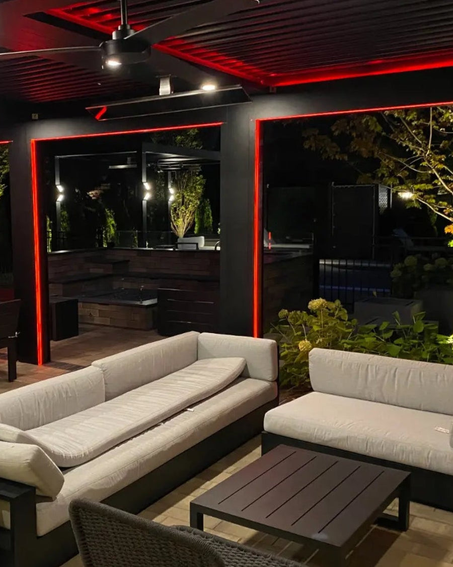 Modern outdoor patio with gray sofa and pergola illuminated with strip lights