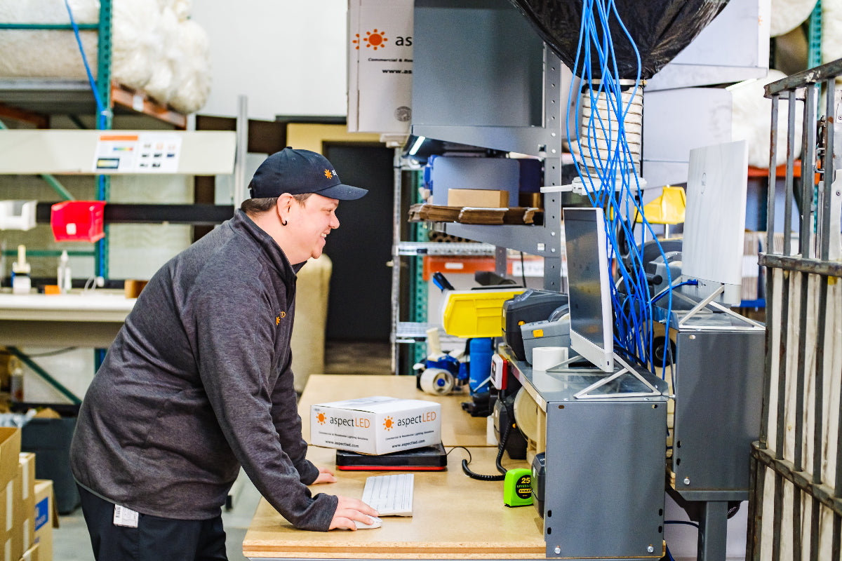 Person working in a warehouse setting with equipment and shelves in the background