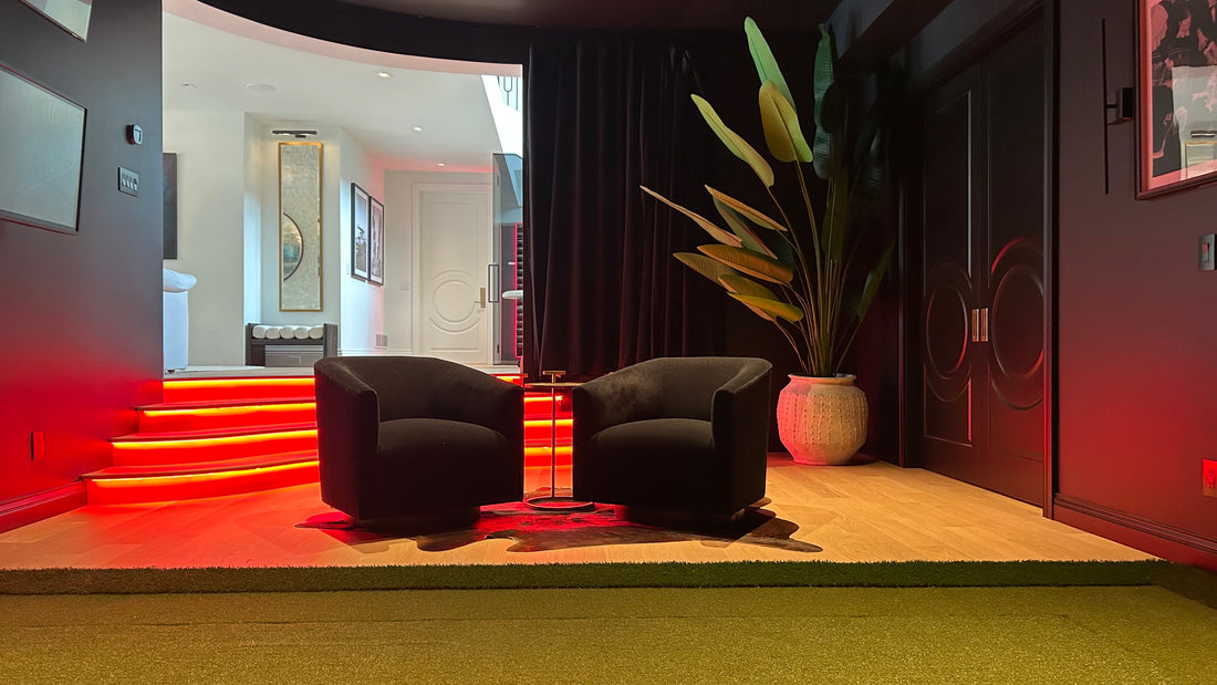 Two gray chairs with red illuminated stairs in the back with a large plant