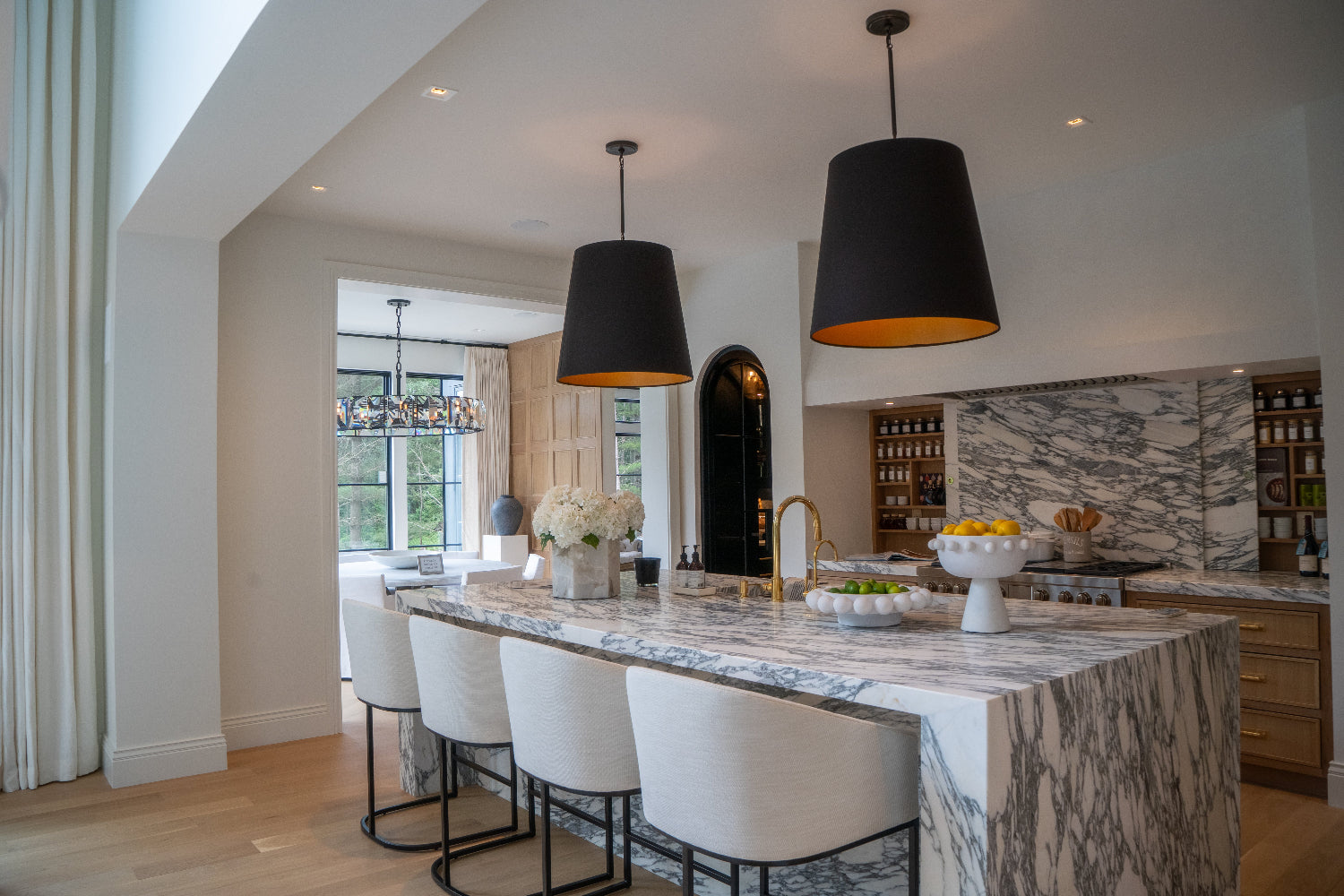Modern kitchen with marble island and pendant lights.