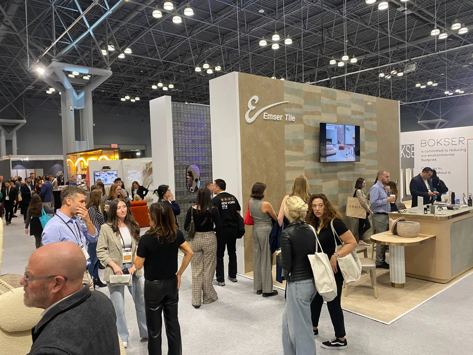Exhibition hall with attendees and booths, including a prominent 'Emser Tile' booth.