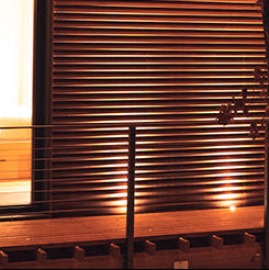 Modern house exterior with wooden shutters and a tree in the foreground at night.