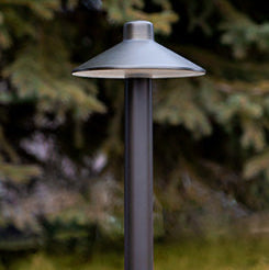 Garden light fixture on a grassy area with trees in the background