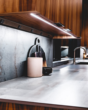 Modern kitchen with stainless steel countertop, wooden cabinets, and decorative items.
