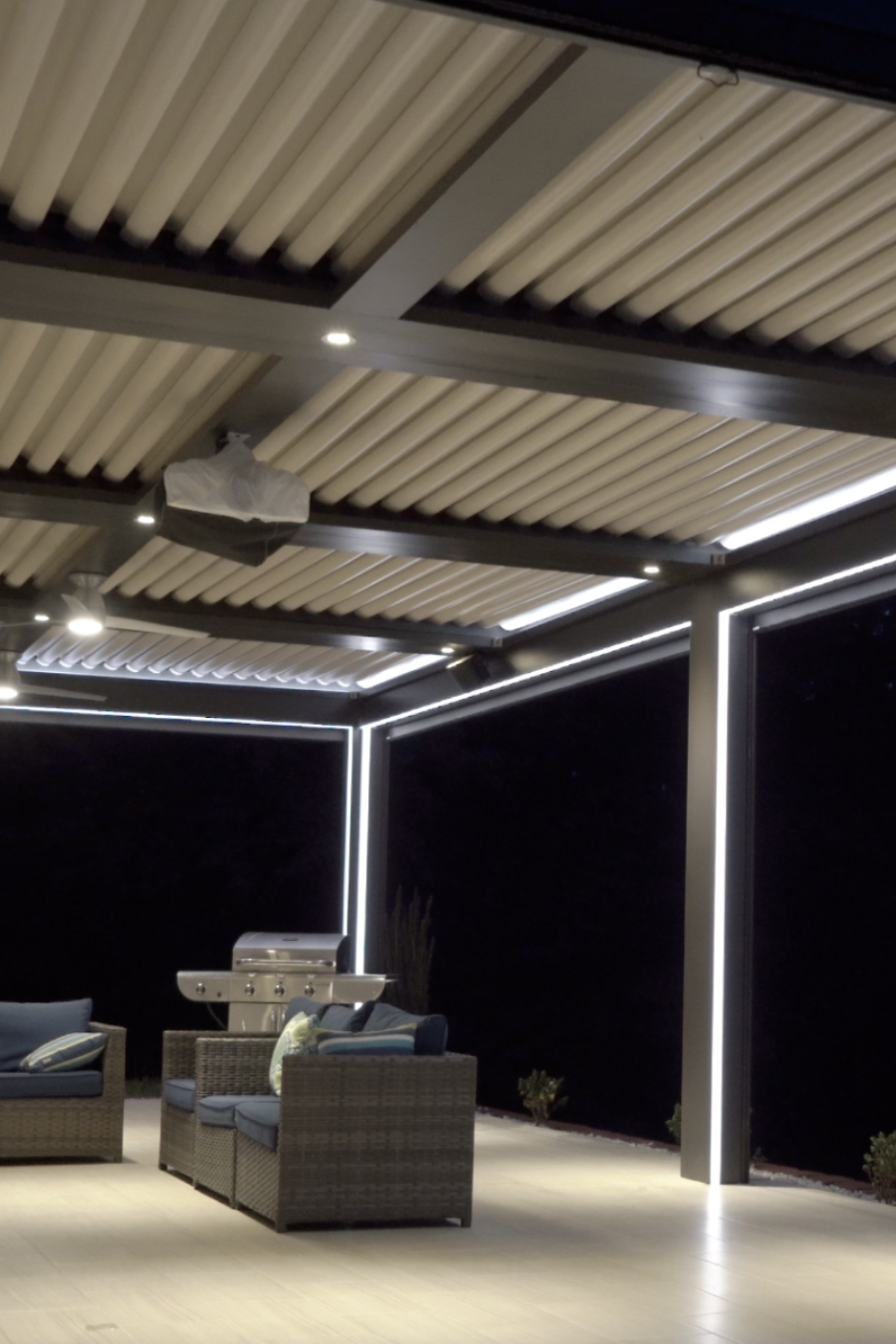 Modern outdoor patio with pergola, seating area, and fire pit at night.