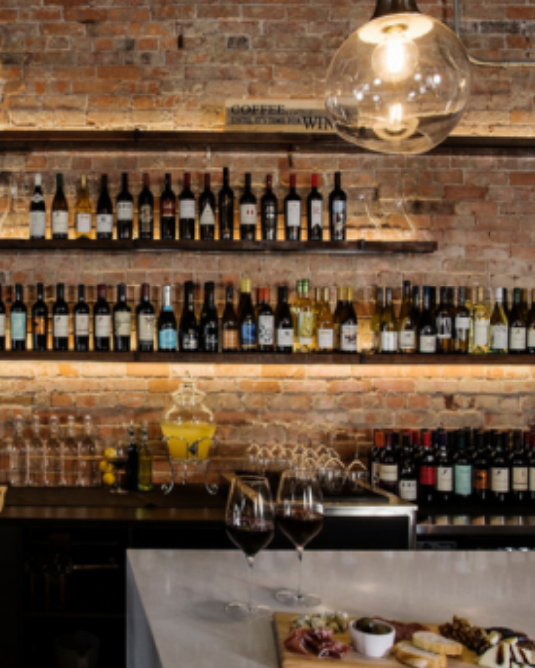 Bar with wine bottles on shelves against a brick wall
